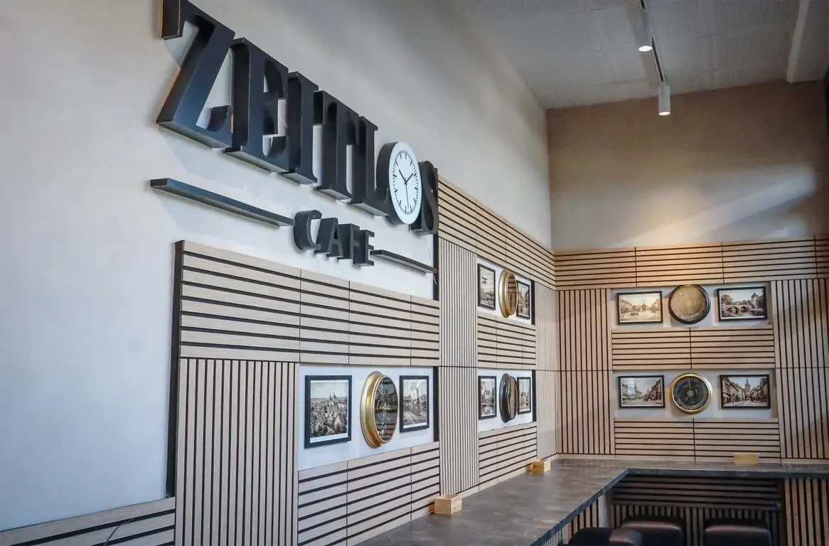 Zeitlos Café — Wand mit ZEITLOS-Schriftzug, Uhr und gerahmten Zeitz-Motiven